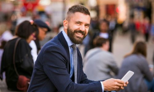 A businessman sitting on the stairs, holding his phone.